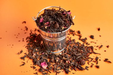 Turuncu arka planda meyve çayıyla dolu küçük bir kova..