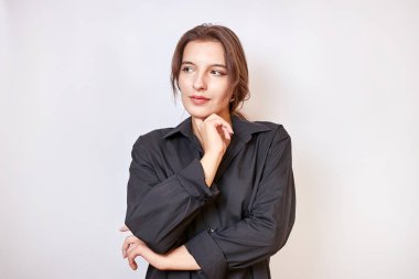 Siyah gömlekli güzel bir kız elleri önünde katlanmış duruyor..