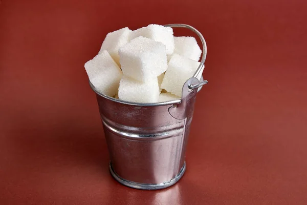 A small bucket with cubes of pressed sugar on a brown background.