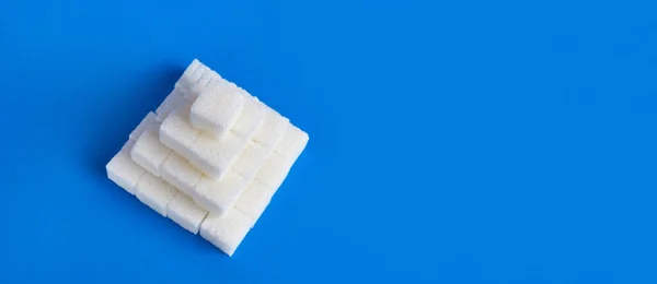 Cubes of pressed sugar stacked in a pyramid on a blue background.