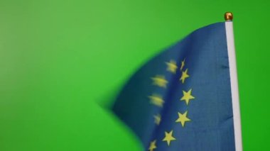 The flag of the European Union flies on a green background.