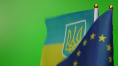 The flag of the European Union and the flag of Ukraine fly on a green background.