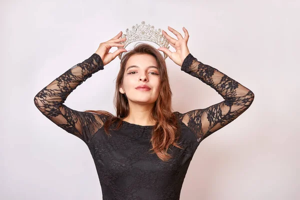 A beautiful girl in a black dress with a crown on her head. Beauty contest concept.