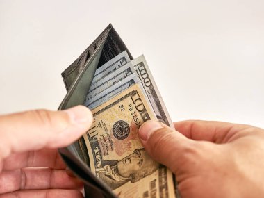 A man looks into a wallet full of dollars on a white background.