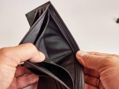 Bir adam beyaz arka planda boş bir cüzdana bakar..