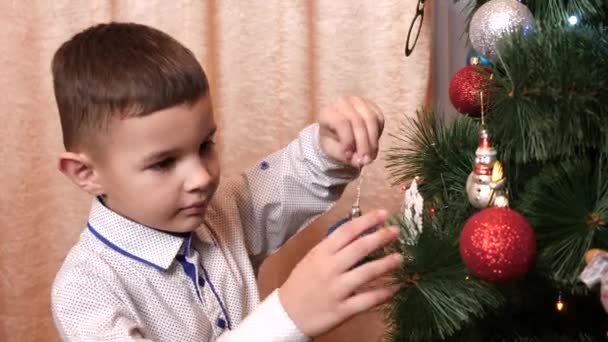 Een Jongetje Hangt Vrolijk Een Kerstversiering Aan Kerstboom — Stockvideo