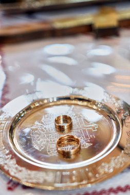 During a church wedding, gold wedding rings lie on the church slab.