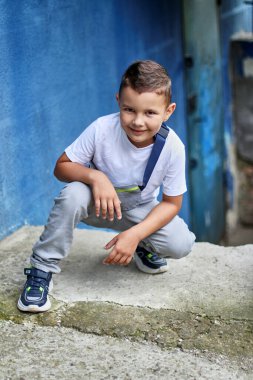 Handsome little boy crouching and posing for the camera. Carefree childhood.
