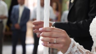 During the wedding ceremony, the bride and groom hold lit candles in their hands.