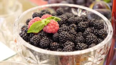 The bowl is filled with ripe blackberries. Buffet table design.