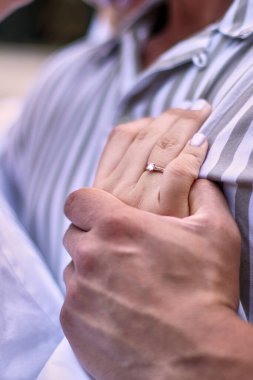 The groom embraces the bride's hand, which has a wedding ring on it. Intimacy, love, family.