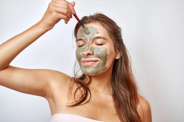 The girl uses blue clay for face care. Beauty concept, skin care cosmetics, facelift. Beauty salon. Wrinkle removal.