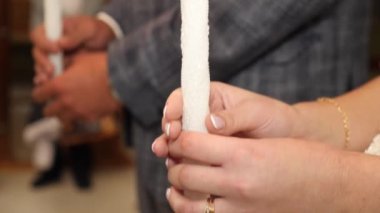 The bride and groom hold candles in the church during the wedding ceremony.