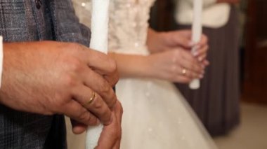 The bride and groom hold candles in the church during the wedding ceremony.