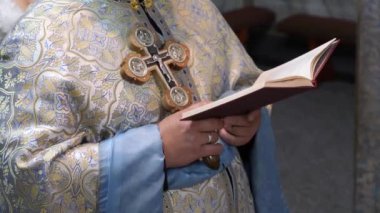 Ayin sırasında, rahip elinde bir haç ve bir kitap tutuyordu..