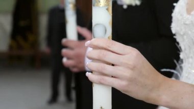 The bride and groom hold candles in the church during the wedding ceremony.