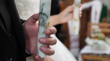 The bride and groom hold candles in the church during the wedding ceremony.