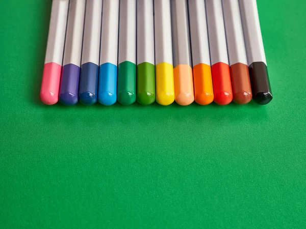 A set of colored pencils on a green background. Stationery for creativity and learning.