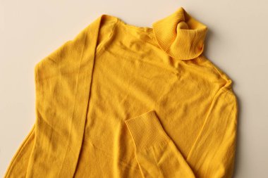 Beyaz arkaplanda sarı yün süveter.