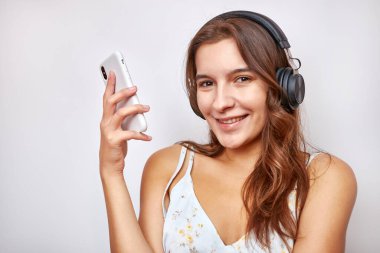 Kulaklıklı güzel bir kız akıllı telefondan müzik dinliyor..