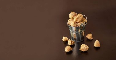 Siyah arka planda küçük bir kovada desenli soya unu parçaları..