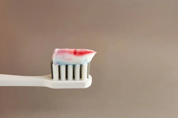 Toothbrush with toothpaste on a gray background. Dental care. Oral hygiene.