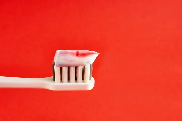 Toothbrush with toothpaste on a red background. Dental care. Oral hygiene.