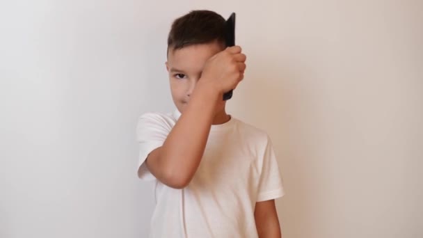 一个可爱的小男孩正试图用梳子梳理他的头发 — 图库视频影像