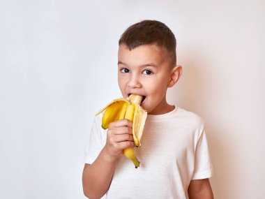Küçük bir çocuk olgun bir muz yiyor. Çocuklar için sağlıklı yiyecekler.