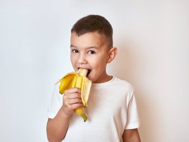 Küçük bir çocuk olgun bir muz yiyor. Çocuklar için sağlıklı yiyecekler.
