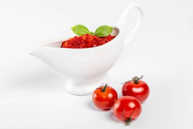 Fesleğen yapraklı ve üç tomalı beyaz sos kasesinde kırmızı sos.