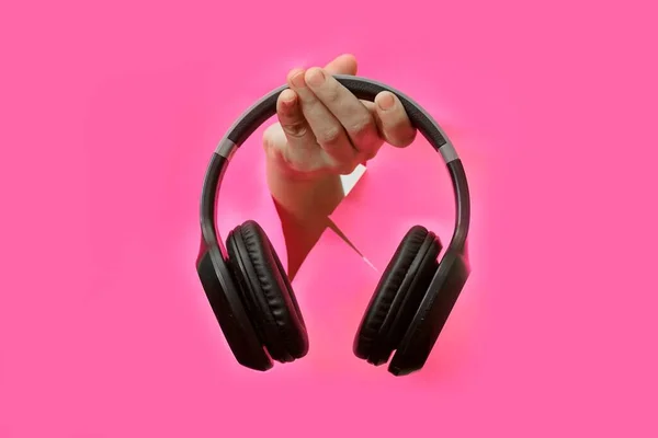 Person Hand Holding Wireless Headphones Ripped Pink Backgro —  Fotos de Stock