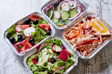 Plastik kaplarda çeşitli sağlıklı salatalar taşıyın.