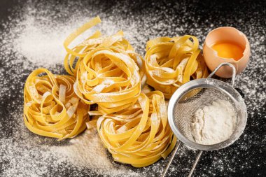 Fettuccine italyan makarnası siyah arka planda serpiştirilmiş fl