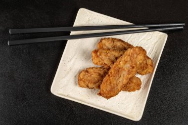 Top view, fish fillet cutlets with chopsticks on dark background