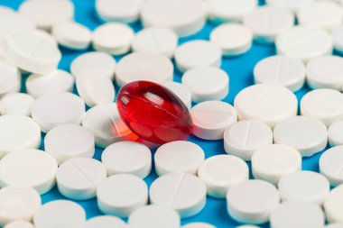 Bir kırmızı kapsül ve bir sürü beyaz tablet.