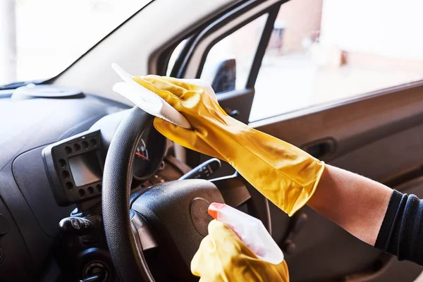Young female sanitizing car interior for covid prevention
