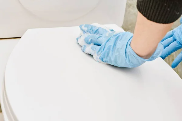 Housewife cleaning toilet seat cover with foamy sponge