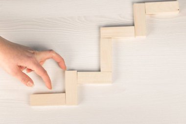 Success concept, hand climbing wooden block stairs on wooden bac