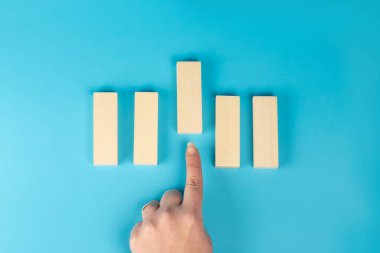 Seçim konsepti, ön taraftaki tahta bloğu gösteren parmaklar, mavi torba.