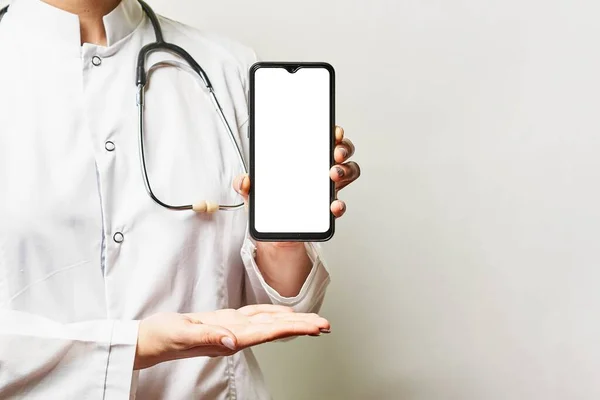 A medical worker holds a smartphone with a blank screen and copy