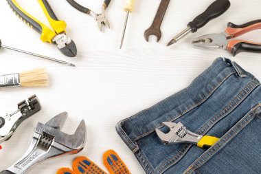 Top view, frame from work tools, glove and jeans on wooden backg