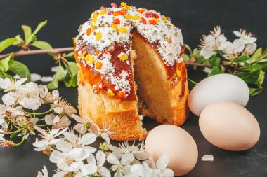 Paskalya pastası, yumurta ve bahar çiçekleri siyah arka planda