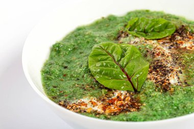 Mangold yaprakları ve baharatlarla dolu bir kasede brokoli kremalı çorba.