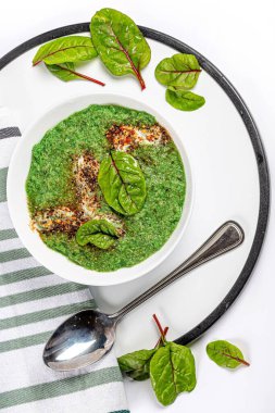 Beyaz kâse içinde yeşil çorba püresi Mangold yaprakları ve kaşıkla, 