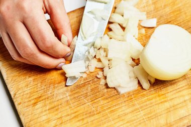 Aşçı soğanı kesme tahtasıyla keser.