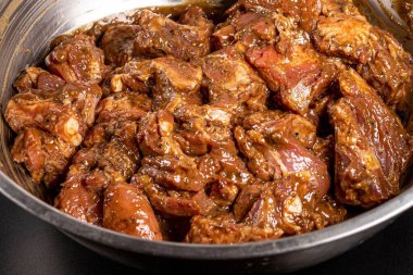 Baharatlı çiğ pirzola ve metal kasede marine edilmiş salamura.
