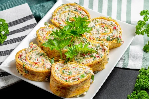 Sliced cheese omelette roll with herbs and crab sticks on a whit