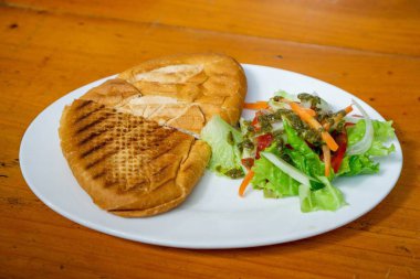 Jambonlu, peynirli ve yanında salatalı sandviç. 