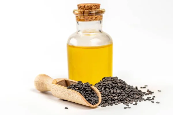 Sesame oil in glass bottle with black sesame seed in wooden scoo